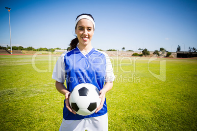 Happy soccer player standing with a ball