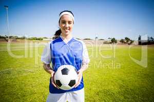 Happy soccer player standing with a ball