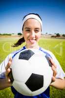 Happy soccer player standing with a ball