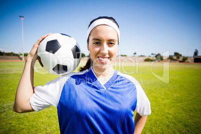 Happy soccer player standing with a ball