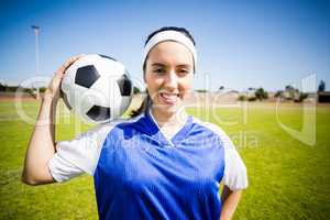 Happy soccer player standing with a ball