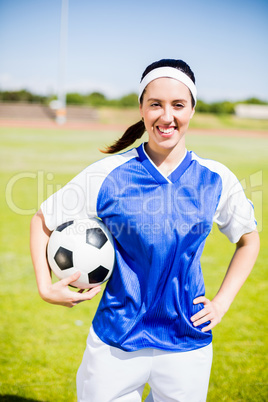 Happy soccer player standing with a ball