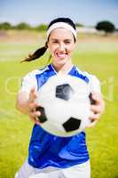 Happy soccer player standing with a ball