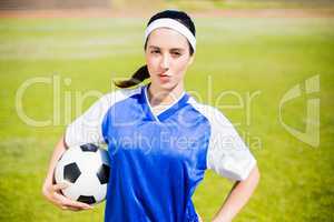 Confident soccer player standing with a ball