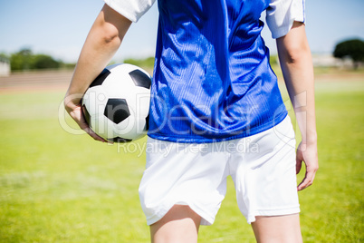 Mid-section of soccer player standing with a ball