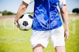 Mid-section of soccer player standing with a ball