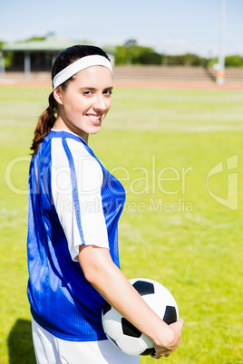 Happy soccer player standing with a ball