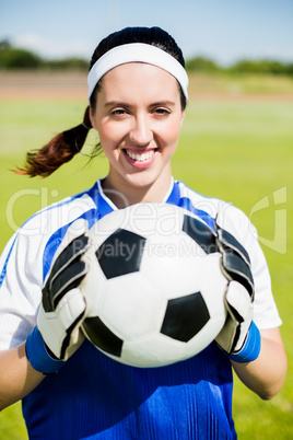 Happy soccer player standing with a ball