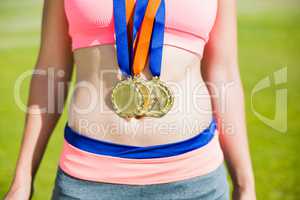 Mid section of female athlete with gold medals around her neck