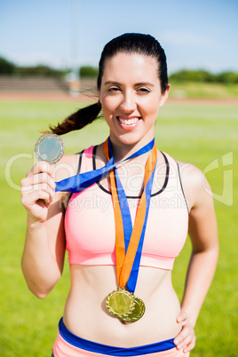 Portrait of female athlete showing her gold medals