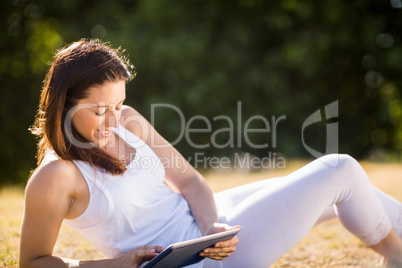 Woman sitting on grass and using digital tablet