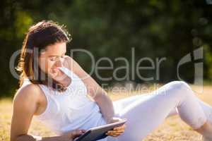Woman sitting on grass and using digital tablet