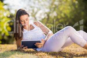 Woman sitting on grass and using digital tablet