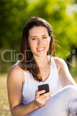 Woman sitting on grass and using mobile phone