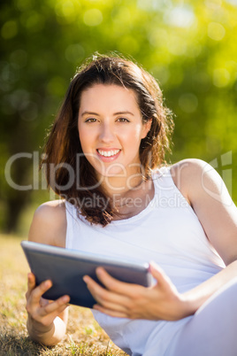 Woman sitting on grass and using digital tablet