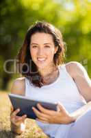 Woman sitting on grass and using digital tablet