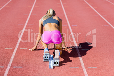 Rear view of female athlete ready to run on running track