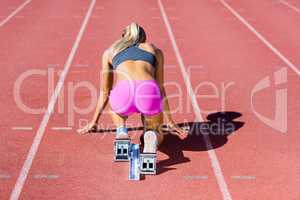 Rear view of female athlete ready to run on running track