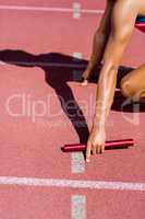 Mid-section of female athlete ready to start the relay race