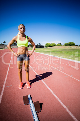 Confident female athlete standing with hand on hip Confident female athlete standing with hand on hip