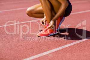 Female athlete tying her shoe laces on running track