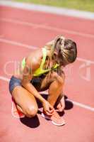 Female athlete tying her shoe laces on running track