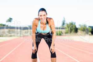 Tired female athlete standing on running track