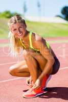 Portrait of female athlete tying her shoe laces on running track