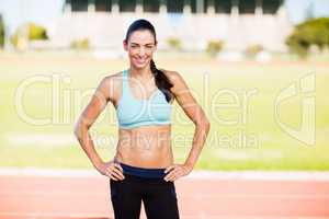 Portrait of female athlete standing with hands on hips