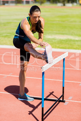 Female athlete warming up above hurdle