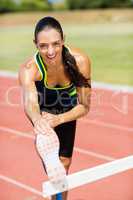 Portrait of female athlete warming up above hurdle