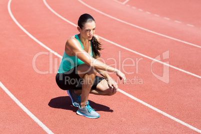 Female athlete kneeling on running track