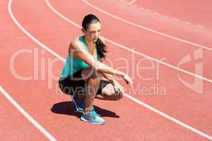 Female athlete kneeling on running track