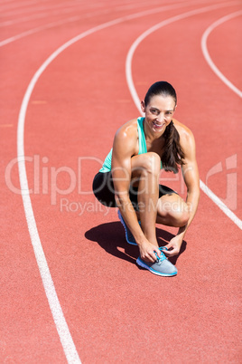 Portrait of happy female athlete tying her running shoes