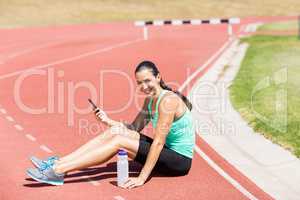 Portrait of happy female athlete using mobile phone