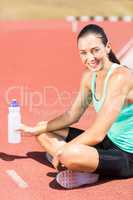 Portrait of tired female athlete sitting with water bottle