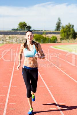 Happy female athlete running on the running track