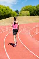 Rear view of female athlete running on the running track