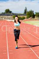 Portrait of happy female athlete running on running track