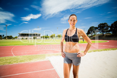 Portrait of female athlete standing with hands on hips