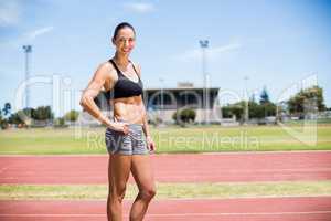 Portrait of female athlete standing with hands on hips