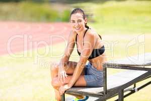 Portrait of happy female athlete sitting on stand