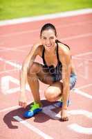 Portrait of female athlete kneeling on running track