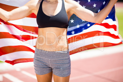 Mid section of female athlete holding up american flag on runnin