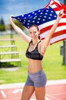 Portrait of female athlete holding up american flag on running t