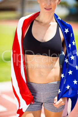 Mid section of female athlete wrapped in american flag on runnin