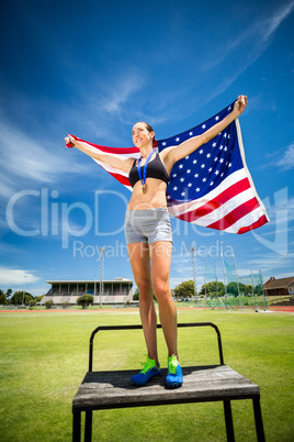 Happy female athlete holding up american flag