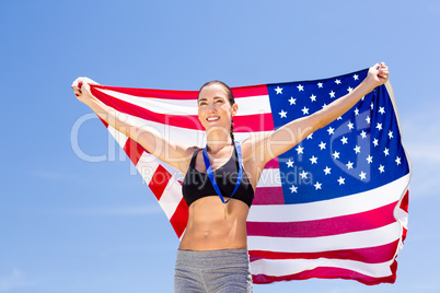 Happy female athlete holding up american flag