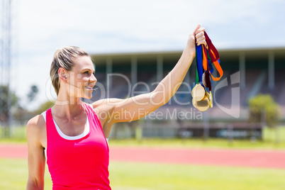 Happy female athlete holding gold medals