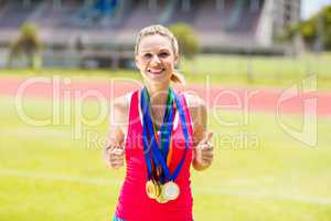 Portrait of happy female athlete with gold medals